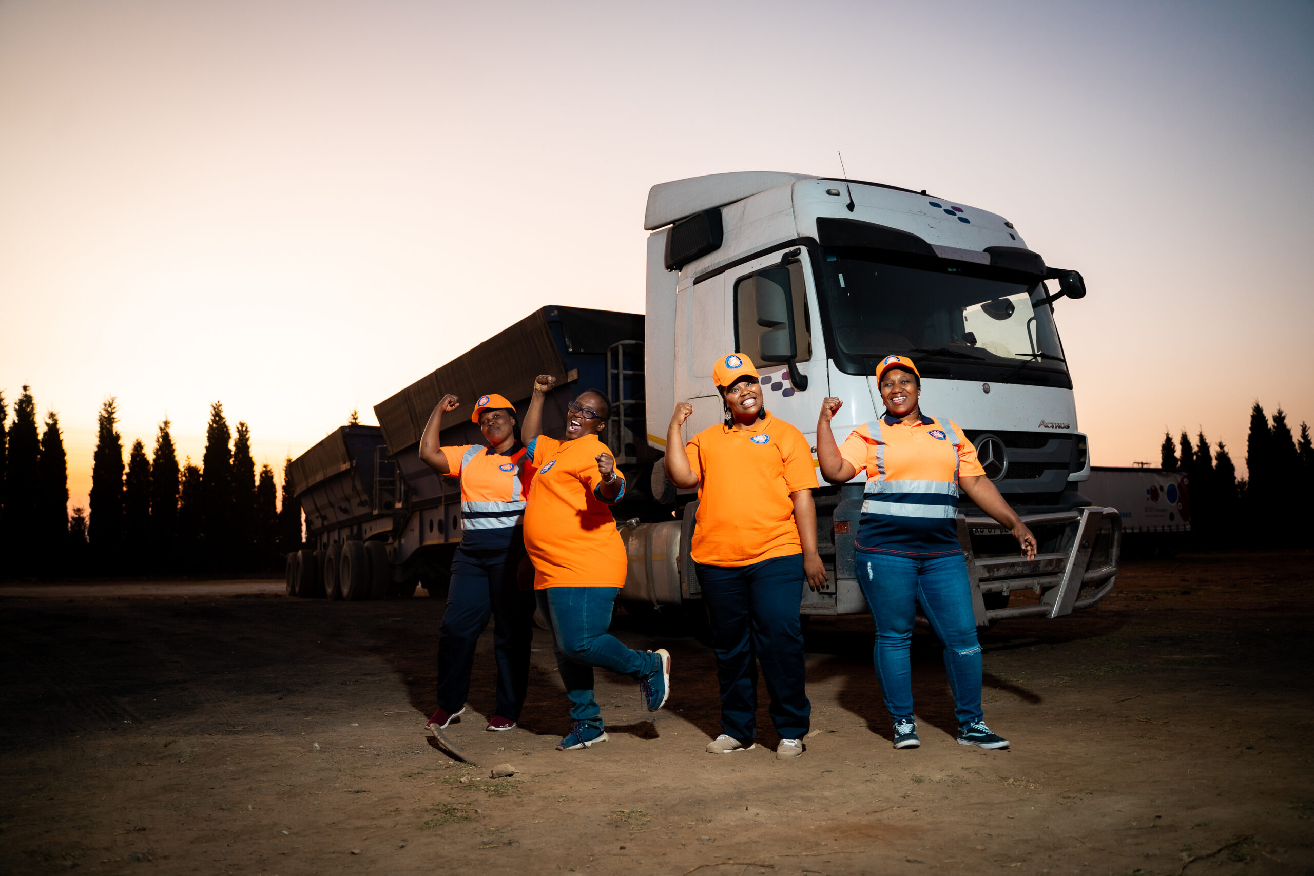 Four women in reflective clothing posing in front of a truck